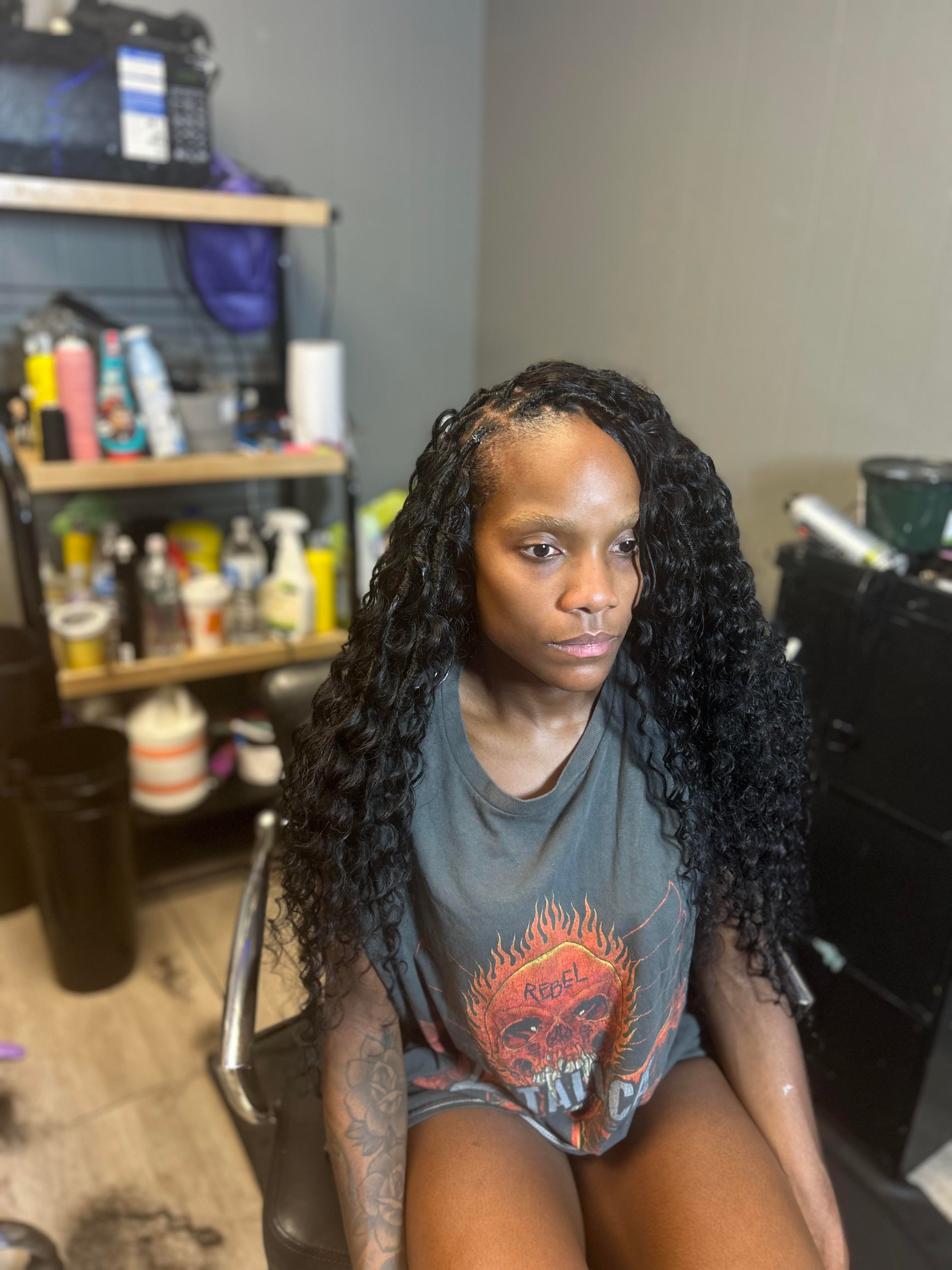Person with curly hair wearing rebel skull t-shirt in home setting