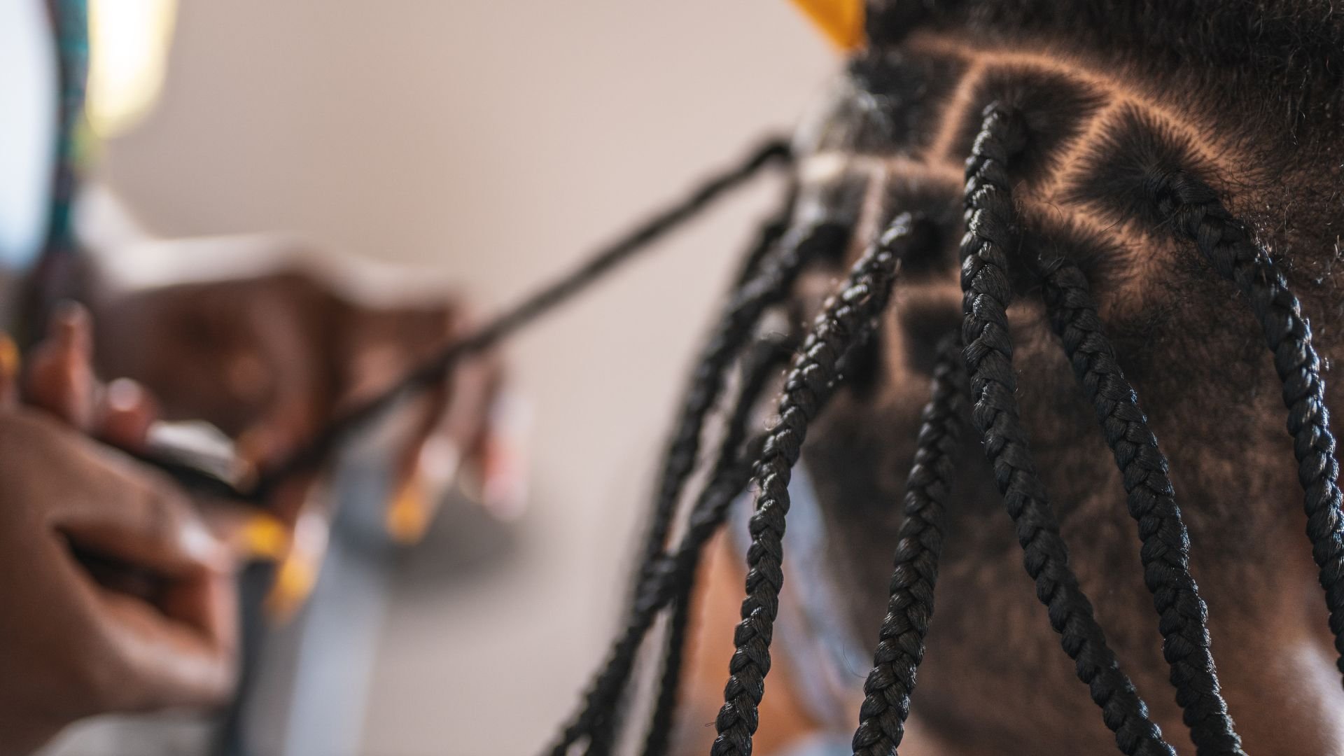 Close-up of tight braids being styled with hair tools